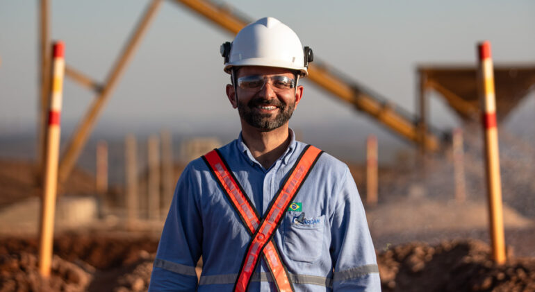 Engenheiro sorridente em ambiente industrial, usando capacete e equipamentos de segurança, representando oportunidades no programa de estágio.