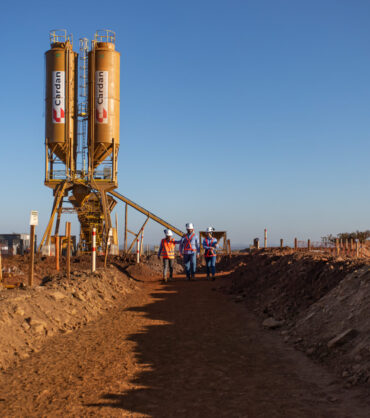 central de concreto móvel central de concreto móvel instalada em uma obra da Cardan e três colaboradores andando próximos a ela.