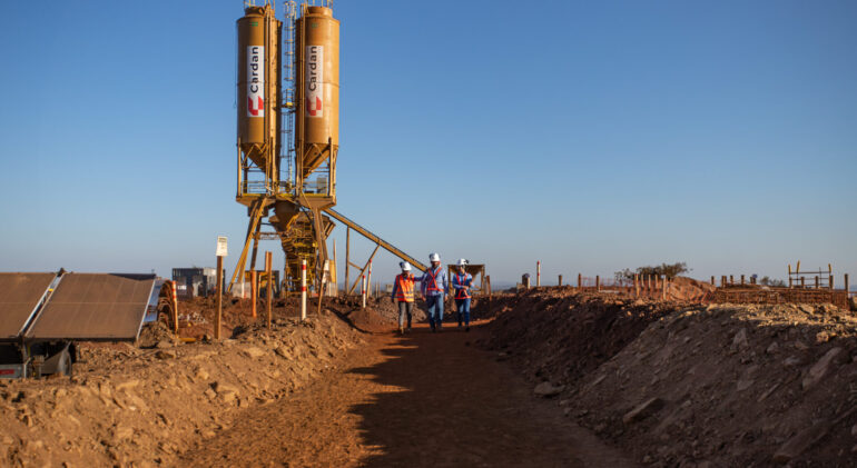 central de concreto móvel instalada em uma obra da Cardan e três colaboradores andando próximos a ela.